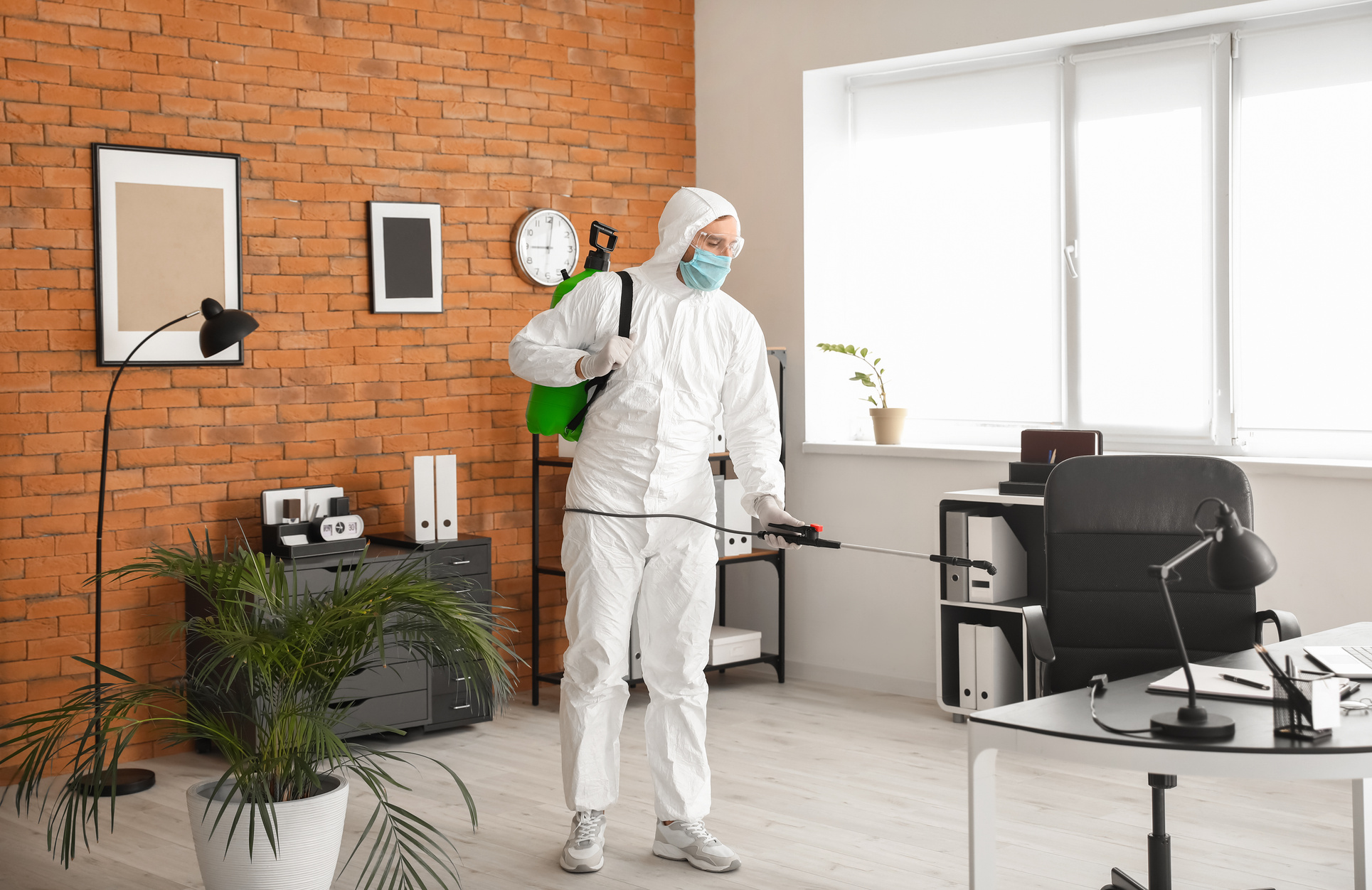 Worker in Biohazard Suit Disinfecting Office